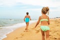 Two positive little girls run along sandy beach Royalty Free Stock Photo