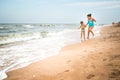 Two positive little girls run along sandy beach Royalty Free Stock Photo