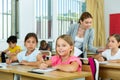 Two positive small school girls sitting together in classroom Royalty Free Stock Photo