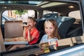 Two positive smiling sisters are happy to eat just cooked Italian pizza sitting in child car seats on the car back seat. Happy Royalty Free Stock Photo