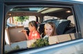 Two positive smiling sisters are happy to eat just cooked Italian pizza sitting in child car seats on the car back seat. Happy Royalty Free Stock Photo