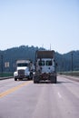 Two big rigs semi trucks dumper and semi tractor are moving towards each other on the way to the bridge Royalty Free Stock Photo