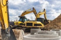Two powerful excavators work at the same time on a construction site, sunny blue sky in the background. Construction equipment for