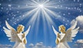 Two praying angels with rays of light over blue sky with stars with copy space in center