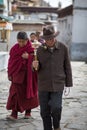 Two praying monks passing in the street