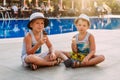 Two pre-school boys in hats sit by the hotel`s outdoor pool and eat ice cream in a waffle cone . Kids and ice cream. Lips in ice