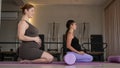 Two pregnant women are sitting on a yoga mat. Prenatal yoga. Royalty Free Stock Photo