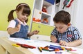 Two preschool children draw with crayons