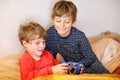 Two preschool or school kids boys, siblings and brothers having fun after school day playing video game at home and Royalty Free Stock Photo