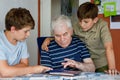 Two Preteen Boys Teaching Grandfather How to Use Internet Safely. Teenage Brothers, School Children with Digital Tablet Royalty Free Stock Photo