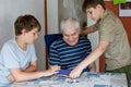 Two Preteen Boys Teaching Grandfather How to Use Internet Safely. Teenage Brothers, School Children with Digital Tablet Royalty Free Stock Photo