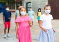 Two preteen girls in protective masks walking along city street