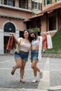 Two pretty Asian female friends are holding their shopping bags, enjoying shopping in the city Royalty Free Stock Photo