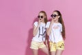 Studio lifestyle portrait of pretty two best friends sister girls, posing and having fun together at pink background Royalty Free Stock Photo