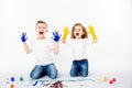 Two pretty child friends boy and girl are drawing pictures by paints. Showing hands in paint, sckream, roar, happy. Royalty Free Stock Photo