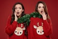 Two pretty crazy best friends in winter sweater having fun with Christmas garlands