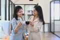 Two female colleagues talking to each other during coffee break at office. Royalty Free Stock Photo