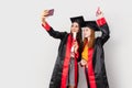 Two pretty female students, celebrating their graduation and making selfie Royalty Free Stock Photo