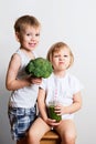 Two pretty fun kids with green smoothies and broccoli over white Royalty Free Stock Photo