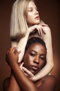 Two pretty girls african and caucasian blond posing cheerful together on browm background, etnithity diverse lifestyle Royalty Free Stock Photo