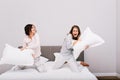 Two pretty girls having pajamas party. They fighting with pillow fight on bed. Royalty Free Stock Photo