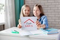 Two pretty girls are holding a Stay at home sign. The sisters are encouraged to stay at home during the quarantine