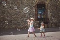 Two pretty little girls are playing with big bubbles in street in summer day Royalty Free Stock Photo