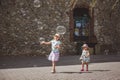 Two pretty little girls are playing with big bubbles in street in summer day Royalty Free Stock Photo