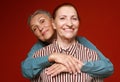 Two pretty older women hugging on red background. Lifestyle concept. Royalty Free Stock Photo