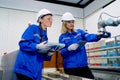 Two pretty professional technician or engineer women help to check the system use controller and ipad with robotic machine in