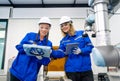 Two pretty professional technician or engineer women help to check the system use controller and ipad with robotic machine in