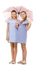 Two Pretty Sisters in Identical Light Dresses Standing Under Umb