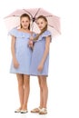Two Pretty Sisters in Identical Light Dresses Standing Under Umb
