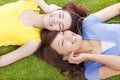 Two pretty young woman lying on grassland and listening music Royalty Free Stock Photo