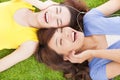 Two pretty young woman lying on grassland and listening music Royalty Free Stock Photo