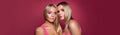 Two pretty young women with makeup and long blonde hair on pink banner background with copy space