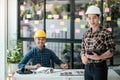 Two Professional Asian architects sitting and standing smiling looking at camera. Royalty Free Stock Photo