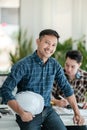 Two Professional Asian architects sitting and standing smiling looking at camera. Royalty Free Stock Photo
