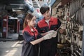 Two Asian mechanic partners discuss hand tools at the car service garage.