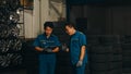 Two professional car mechanic using paperwork makes the oil and engine check to the car on lifted automobile at repair service