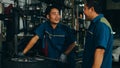 Two professional car mechanic using paperwork makes the oil and engine check to the car on lifted automobile at repair service