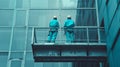 Two professional cleaners standing on aerial work platform and washing glass facade of modern commercial building Royalty Free Stock Photo