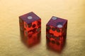 Two professional dice made of red glass. Cubes on a gold background in the backlight. The result is one and two