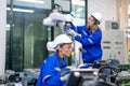 Two professional engineers or technician worker women help to check and maintenance robotic arm machine in factory workplace with