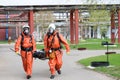 Two professional firefighter firefighters in orange protective fireproof suits, white helmets and gas masks carry the injured pers