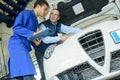 Two professional mechanics inspecting car engine at their garage