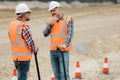 professional road construction workers in orange vests and protective helmets in the middle on the terrain