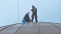 Two professional steeplejacks are working at the domed roof