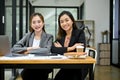 Two professional Asian businesswomen in formal outfit sitting at the office desk together Royalty Free Stock Photo