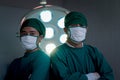 Two professional surgeon doctor standing under bright light, using surgical equipment to do surgery at hospital operating room. Royalty Free Stock Photo